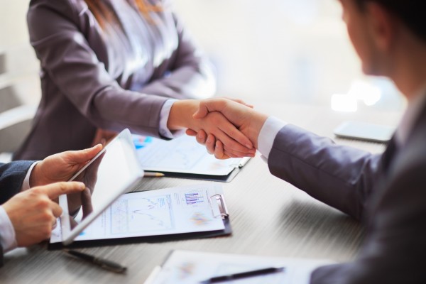 corporate finance photo via hand shake in office between employees